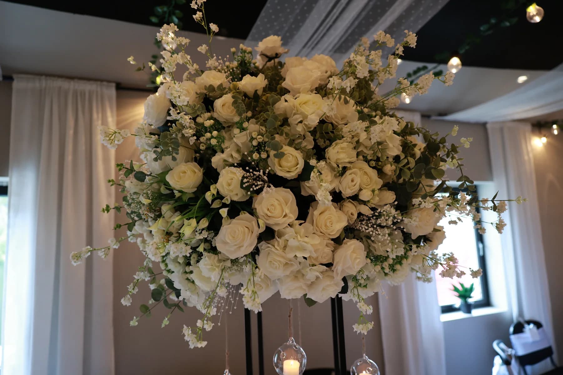 Høy hvit og grønn blomsterdekorasjon over festbord